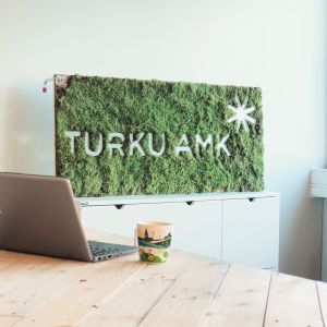 Pöydällä tietokone ja kahvikuppi